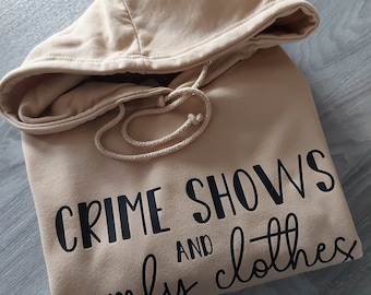 May include: A tan hoodie with the text "CRIME SHOWS AND comfy clothes" printed in black.