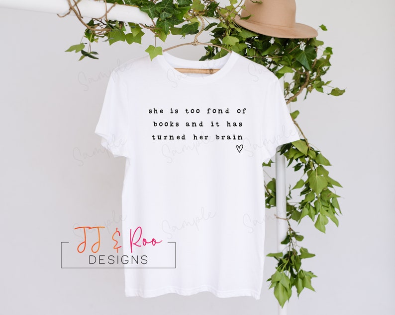 May include: White t-shirt with black text that reads "she is too fond of books and it has turned her brain" with a small heart symbol.