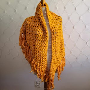May include: A crocheted shawl in a bright yellow color with fringe on the edges.
