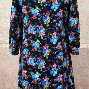 May include: A black dress with a floral print featuring blue, pink, and gold flowers. The dress has a long sleeve and a collar.