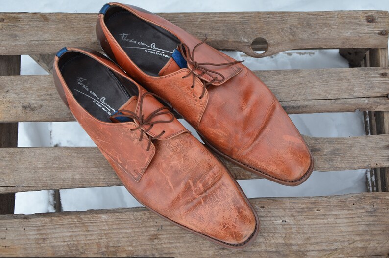 May include: A pair of brown leather lace-up shoes with a pointed toe. The shoes have a blue and white label on the inside that reads "Franco Cuomo, Florence Made in Italy".