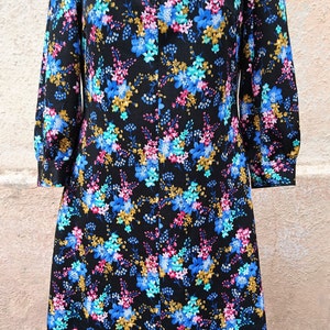 May include: A black dress with a floral print in shades of blue, pink, and gold. The dress has a long zipper down the front and a collar.