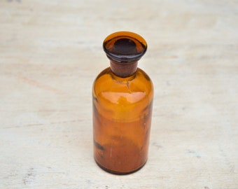 Botella de medicina de vidrio pequeña vintage con tapón de vidrio. Tarro de boticario ámbar. Botella de farmacia redonda marrón con tapas