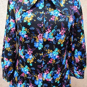 May include: A black long-sleeved dress with a floral print in shades of blue, pink, and gold. The dress has a zipper closure and a large collar.