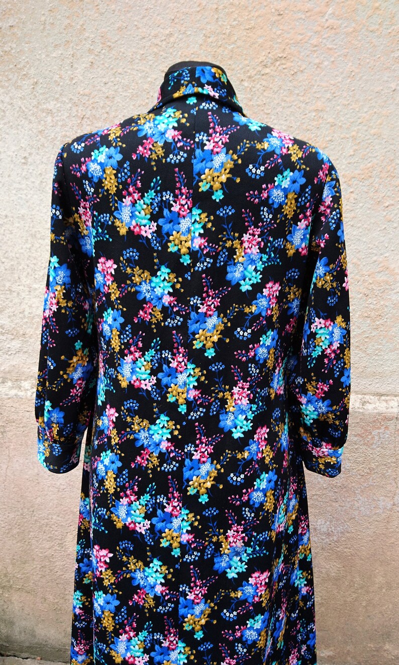 May include: A long-sleeved dress with a black background and a floral print in shades of blue, pink, and gold.