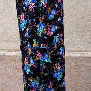 May include: A black dress with a floral print featuring blue, pink, and yellow flowers. The dress has a round neckline and three-quarter sleeves.