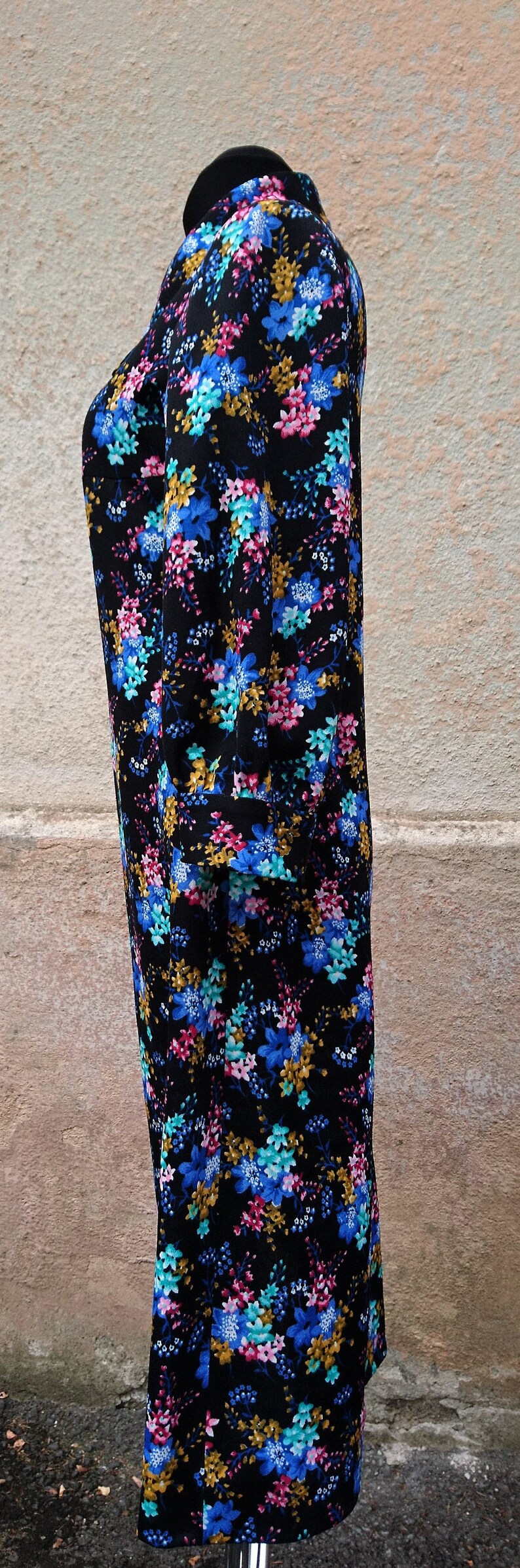 May include: A black dress with a floral print featuring blue, pink, and yellow flowers. The dress has a round neckline and three-quarter sleeves.