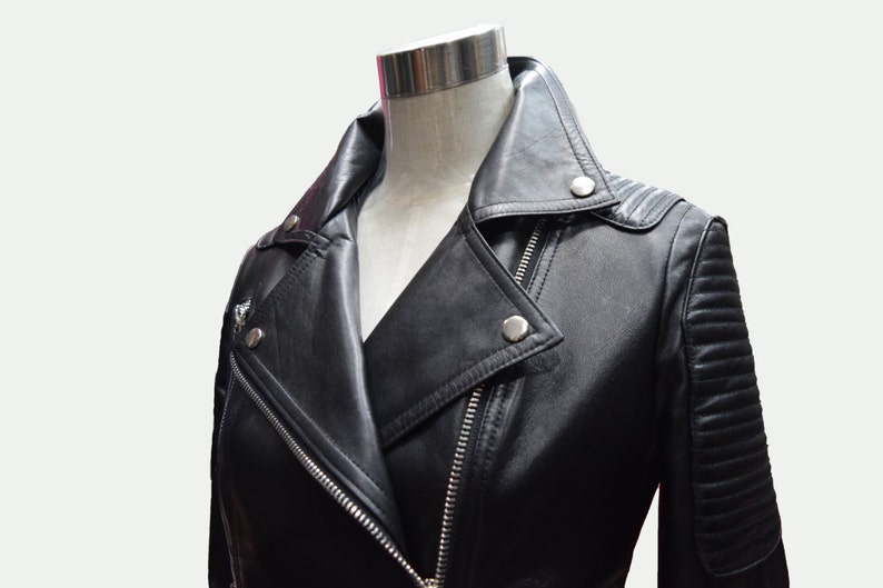 May include: Black leather motorcycle jacket with a zipper closure and a stand-up collar. The jacket has a quilted design on the sleeves and a zippered pocket on the left side.