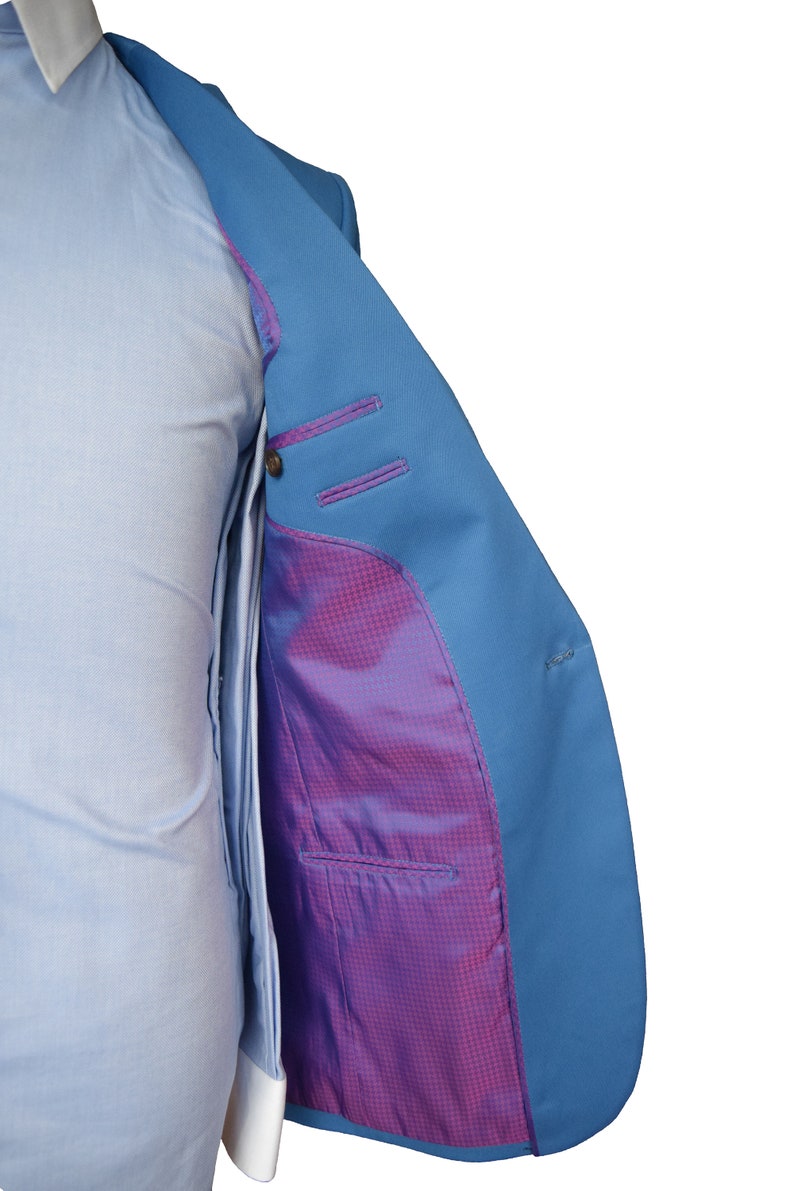 May include: A light blue blazer with a purple and white checkered lining. The blazer is unbuttoned and the lining is visible.