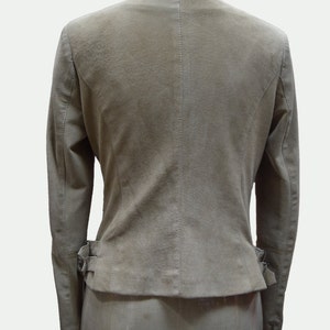 May include: A light brown suede jacket with a zipper closure and a belt at the waist.