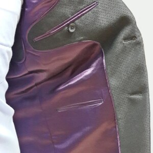 May include: A gray blazer with a purple satin lining. The blazer has a button closure and two pockets on the inside.