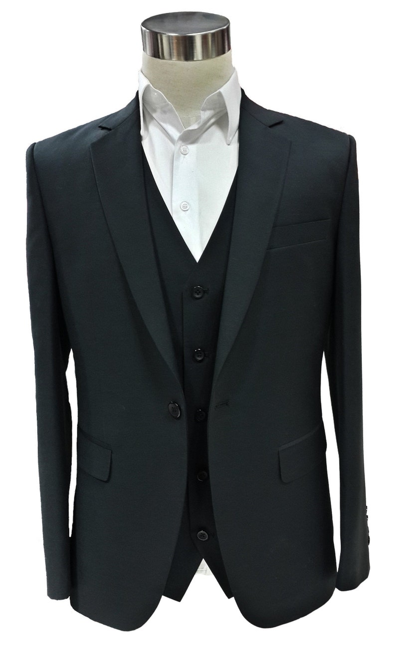 May include: A black three-piece suit displayed on a mannequin. The suit includes a jacket, vest, and dress shirt. The jacket has two front pockets and a notched lapel. The vest has a button-down closure. The white dress shirt is visible beneath the vest.