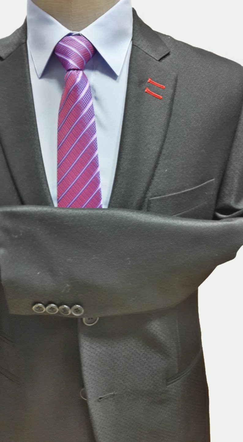 May include: A black suit jacket with a buttoned closure and a single button on the front. The jacket has a striped purple and pink tie with a white shirt underneath.