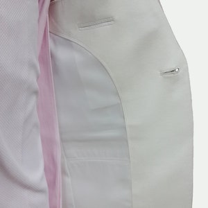 May include: A white blazer with a single button closure and a pocket on the inside. The blazer is unbuttoned and the inside lining is visible.