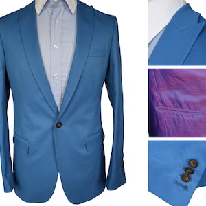 May include: A light blue blazer with a single button closure. The blazer has a notched lapel and a plain front. The lining is a pink and white checkered pattern.