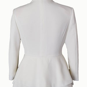 May include: A white blazer with a peplum hem and long sleeves.