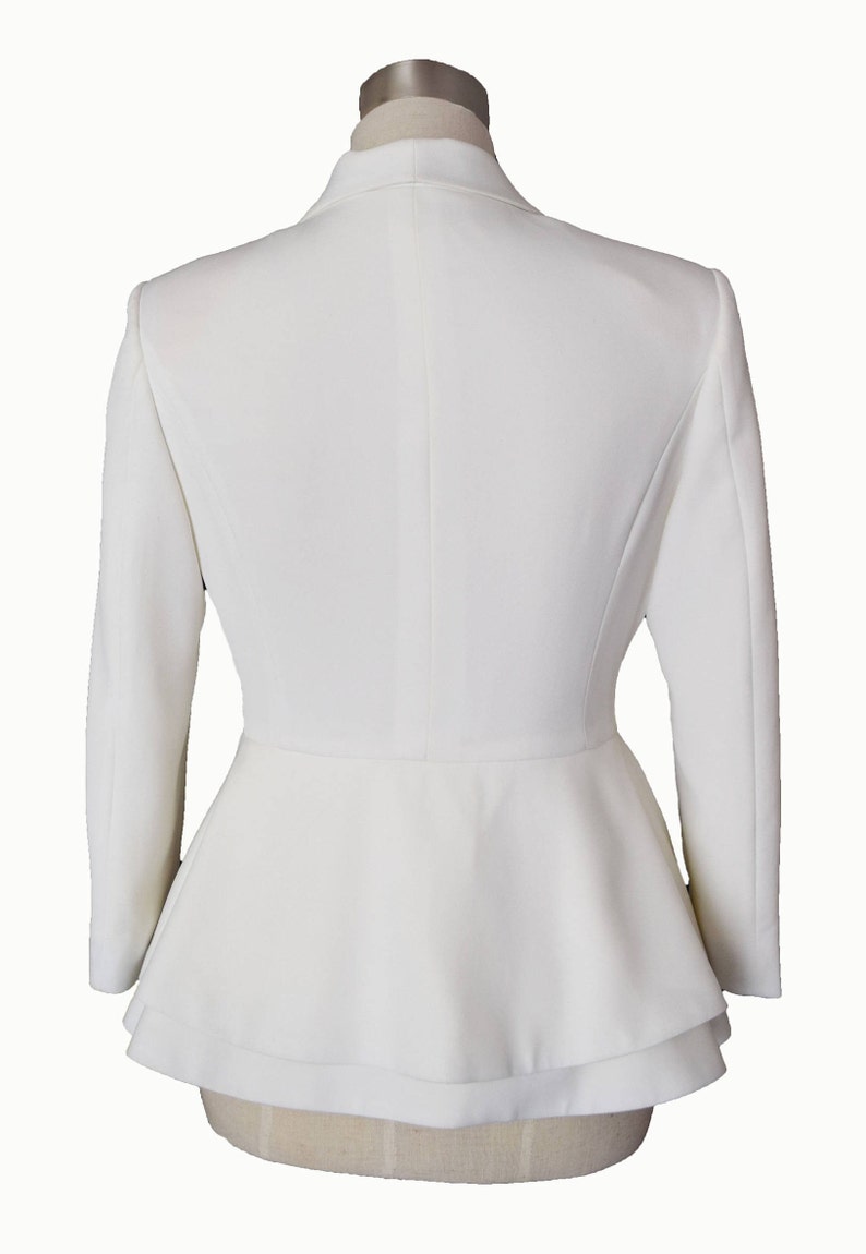 May include: A white blazer with a peplum hem and long sleeves.