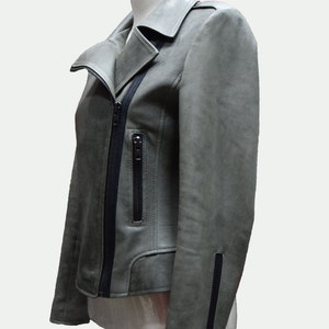 May include: A gray leather jacket with a black zipper and black trim. The jacket has a collar and a zippered pocket on the left side.