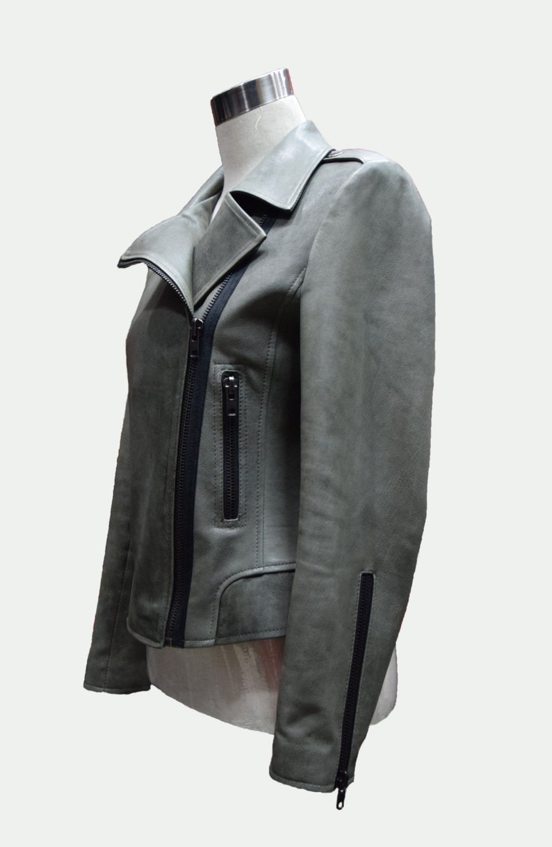 May include: A gray leather jacket with a black zipper and black trim. The jacket has a collar and a zippered pocket on the left side.