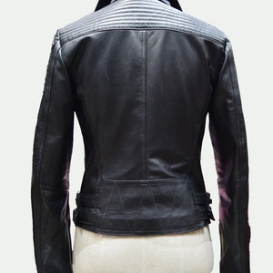 May include: Black leather jacket with a zipper closure and a stand-up collar. The jacket has a quilted design on the back and a belt at the waist.