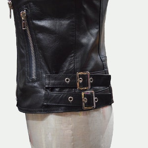 May include: Black leather jacket with a zipper closure and two buckle straps at the waist.
