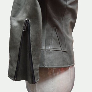 May include: A green leather jacket with a zipper on the sleeve. The jacket is on a white mannequin.