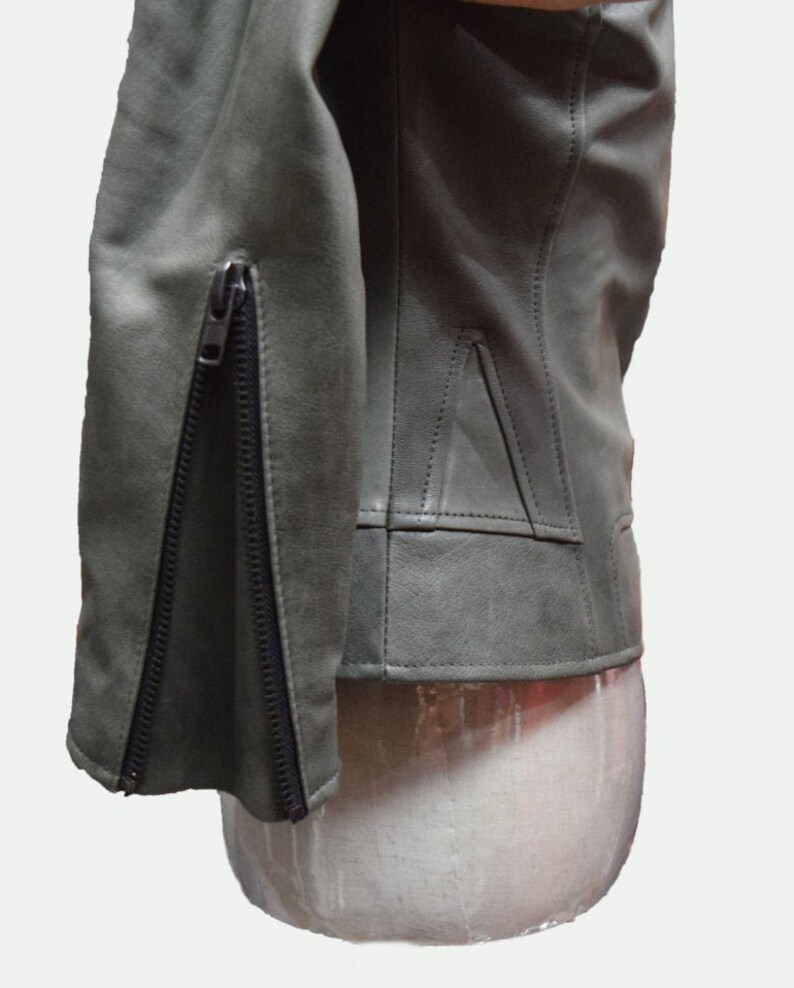 May include: A green leather jacket with a zipper on the sleeve. The jacket is on a white mannequin.
