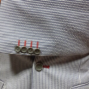 May include: A striped blue and white blazer with a blue patterned tie and four buttons on the left side of the jacket.