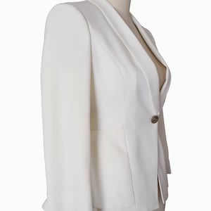 May include: A white blazer with a single button closure and a slightly flared hem.