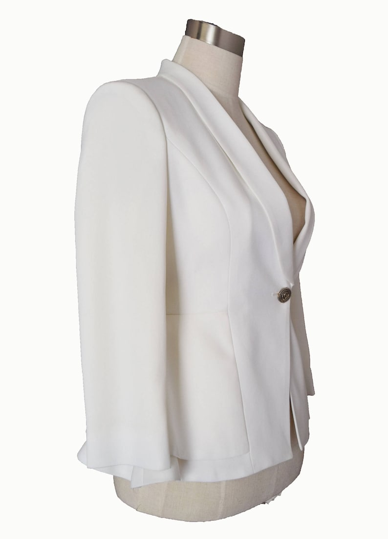 May include: A white blazer with a single button closure and a slightly flared hem.
