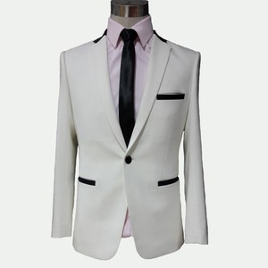 May include: A white suit jacket with black trim and a single button closure. The jacket is worn over a pink dress shirt with a black tie.