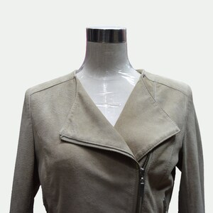 May include: A beige suede jacket with a zipper closure and a v-neck collar.