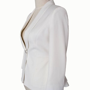 May include: A white blazer with a single button closure and a slightly flared hem.