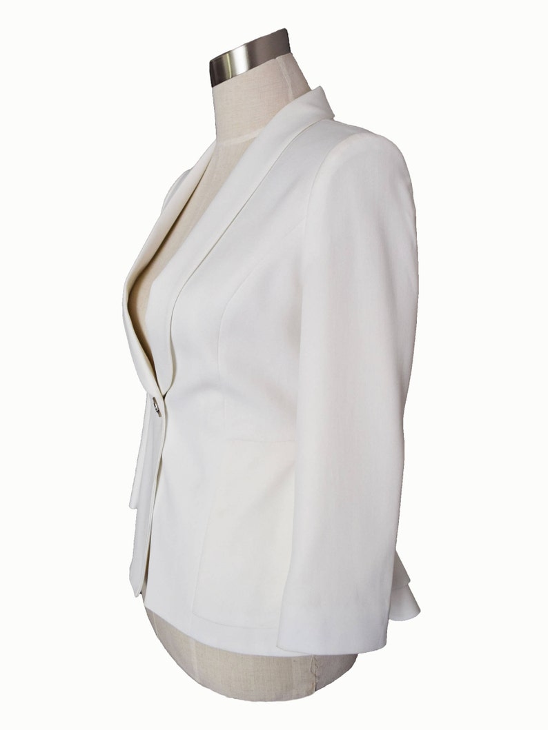 May include: A white blazer with a single button closure and a slightly flared hem.