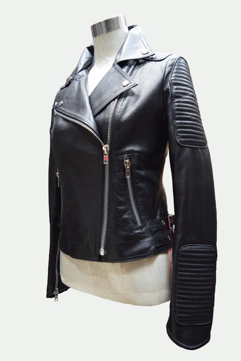 May include: Black leather motorcycle jacket with a zipper closure, a stand-up collar, and zippered pockets. The jacket has a quilted detail on the sleeves.