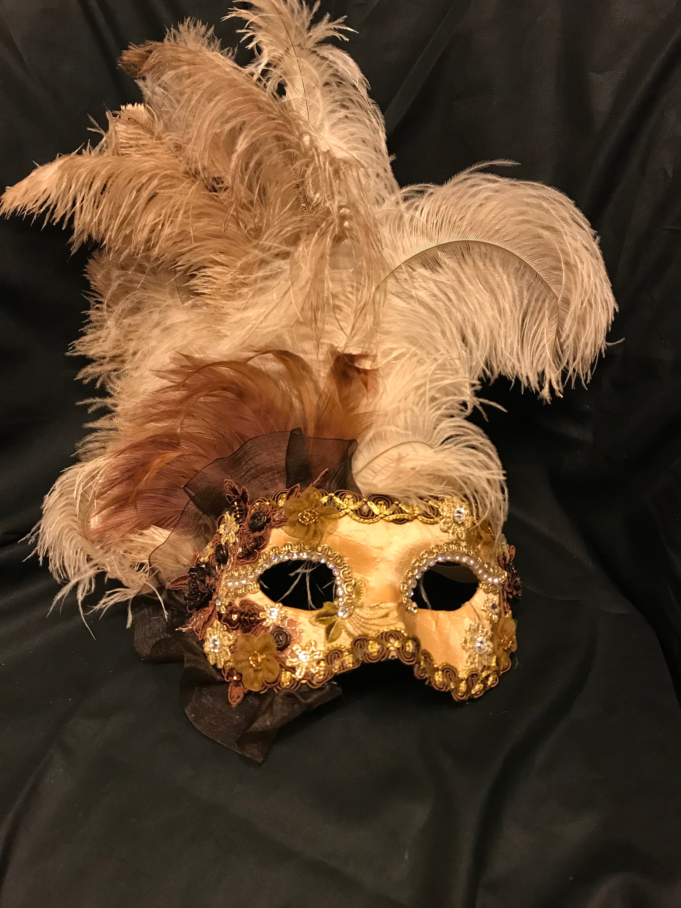 Lv Mardi Gras Sequined Mask Decorated With Feathers On A Bed Of