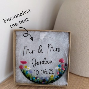 May include: A clear glass bauble with a floral design and the text "Mr & Mrs Jordan 10.06.22".