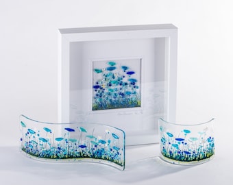 Puede incluir: Dos piezas de arte floral de vidrio azul y verde, una en un marco blanco y dos piezas curvas. La pieza enmarcada tiene el texto "Cornflowers" en cursiva.