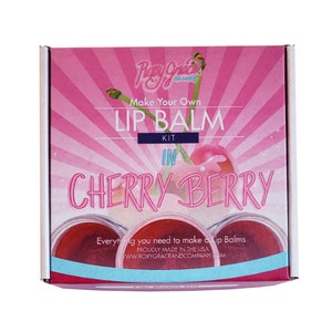 May include: Pink box with a cherry graphic and the text "Make Your Own Lip Balm Kit in Cherry Berry". The box is for a lip balm making kit.