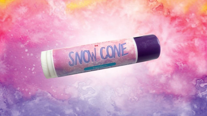 Puede incluir: Un tubo cil&iacute;ndrico de b&aacute;lsamo labial con tapa morada y base blanca. La etiqueta presenta un fondo de acuarela rosa y morado con el texto "SNOW CONE" en letras azules, junto a un peque&ntilde;o rect&aacute;ngulo color verde azulado etiquetado "Ingredients".