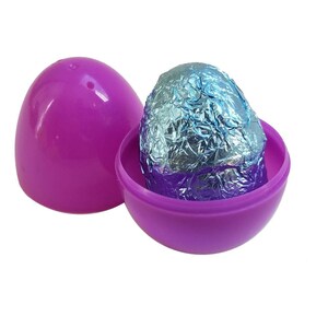 May include: A purple plastic egg, opened to reveal a foil-wrapped bath bomb egg. The foil has blue and silver tones. The other half of the egg is next to the open half. The background is white.