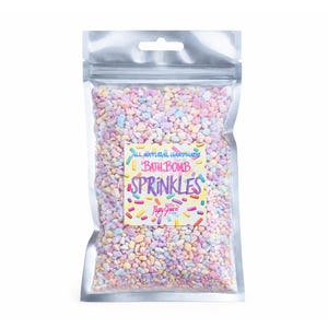 May include: A clear, resealable bag filled with colorful, pastel-colored bath bomb sprinkles. The bag features a label with the words "All Natural Handmade Bath Bomb Sprinkles" in a playful font, with a colorful sprinkle design.