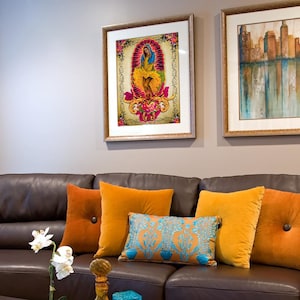 Puede incluir: Un sof&aacute; de cuero marr&oacute;n con almohadas de color naranja y amarillo. Una bandeja turquesa con botellas de vidrio decorativas y una orqu&iacute;dea en maceta se encuentra en una mesa de caf&eacute; frente al sof&aacute;.