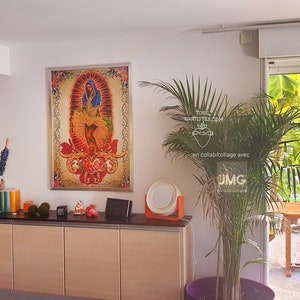 Puede incluir: Una impresi&oacute;n enmarcada de una imagen religiosa colorida con una mujer con un vestido azul y un fondo rojo. La impresi&oacute;n est&aacute; colgada en una pared blanca en una habitaci&oacute;n con una planta grande y una ventana que da a un patio.