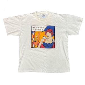 May include: White t-shirt with a colorful graphic print of a woman holding a glass of orange juice. The graphic includes the text "By Eck it's Gorgeous".