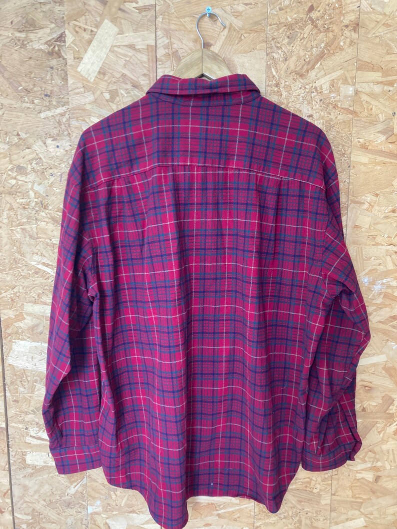 May include: A red and black checked flannel shirt with long sleeves and a button-up front.