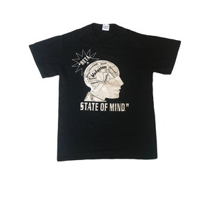 May include: Black t-shirt with a white graphic of a head with a brain divided into sections with words like "Volunteer", "Service", "Integrity", and "Cooperation". The text "STATE OF MIND." is below the graphic.
