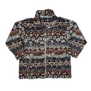 May include: A zip-up fleece jacket with a patterned design in shades of brown, gray, and white. The jacket has a high collar and a full-length zipper. The pattern appears to be a knit-like design.