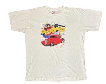 May include: White t-shirt featuring a graphic print of a red car, a jukebox, and a woman in a dress. The text "Splindletop" is printed on the graphic.