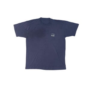 May include: A navy blue t-shirt with short sleeves. The shirt has a small graphic on the upper left chest area. The graphic includes text and a logo. The shirt is made of a soft, comfortable material.